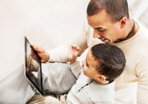 Father teaching his son how to use a touchpad.